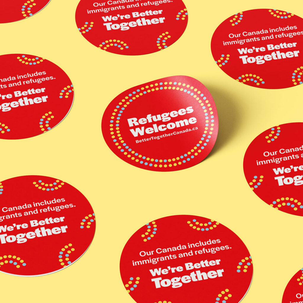 A selection of red stickers reading "Better Together" and "Our Canada includes immigrants and refugees."