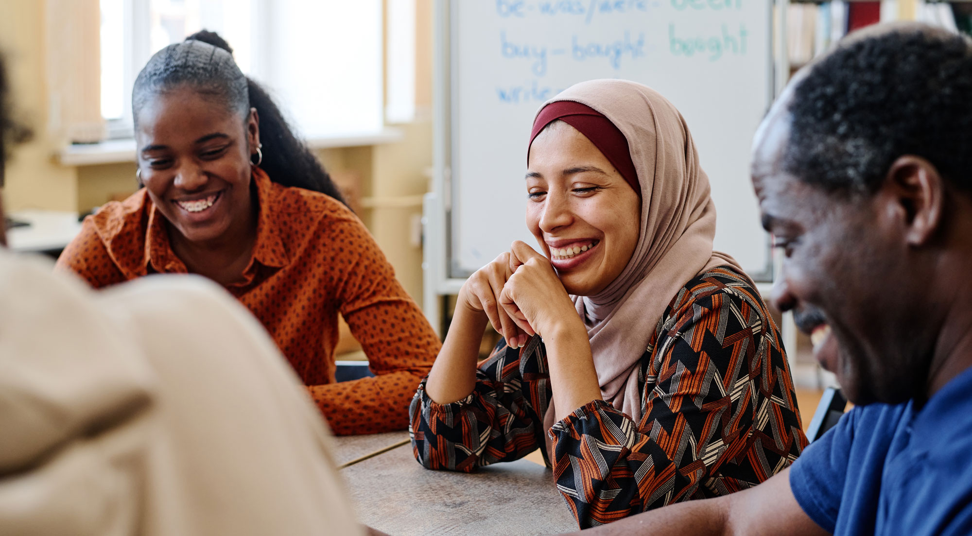 Group of modern immigrants sitting at table having fun laughing